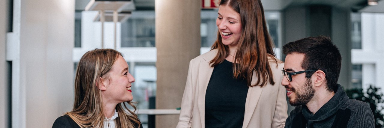 Laughing young graduates in a team discussion as they work together on the laptop in front of them.