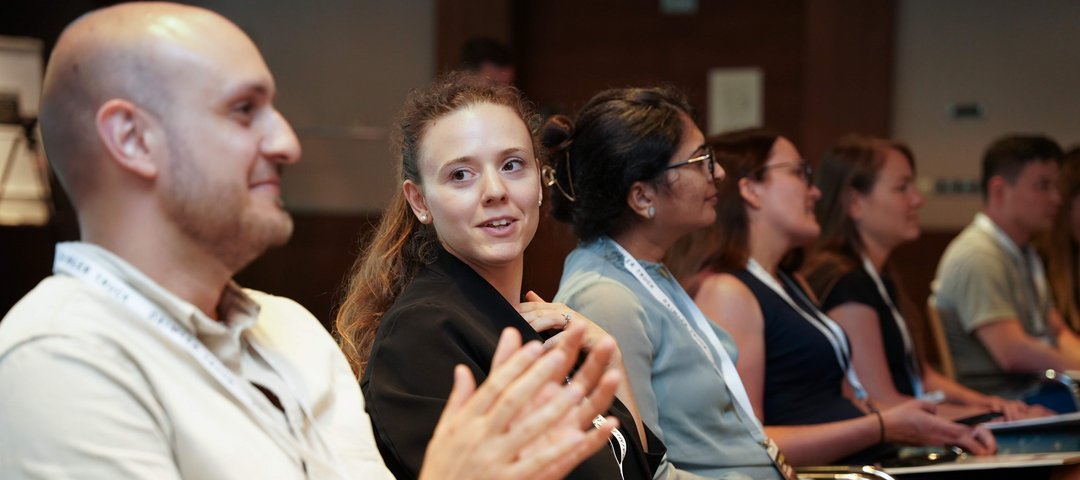 A group of trainees in a seminar room listening attentively to a presentation.