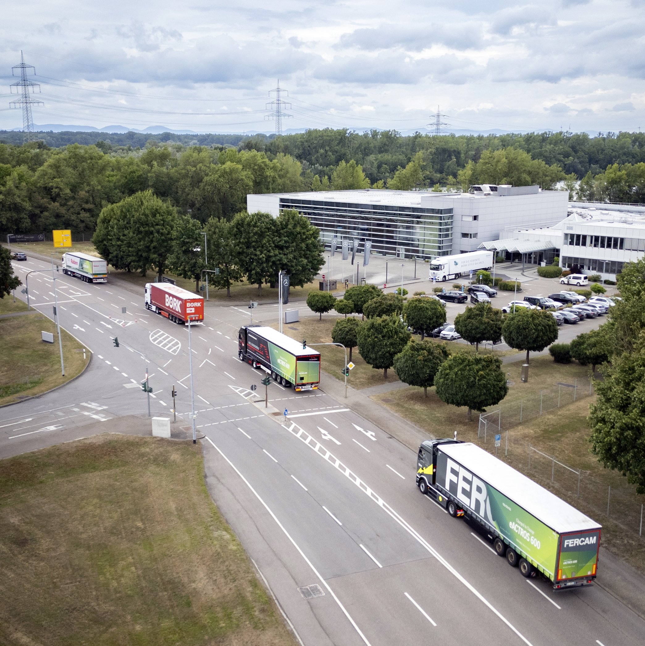 Several battery-electric Mercedes-Benz trucks drive behind each other