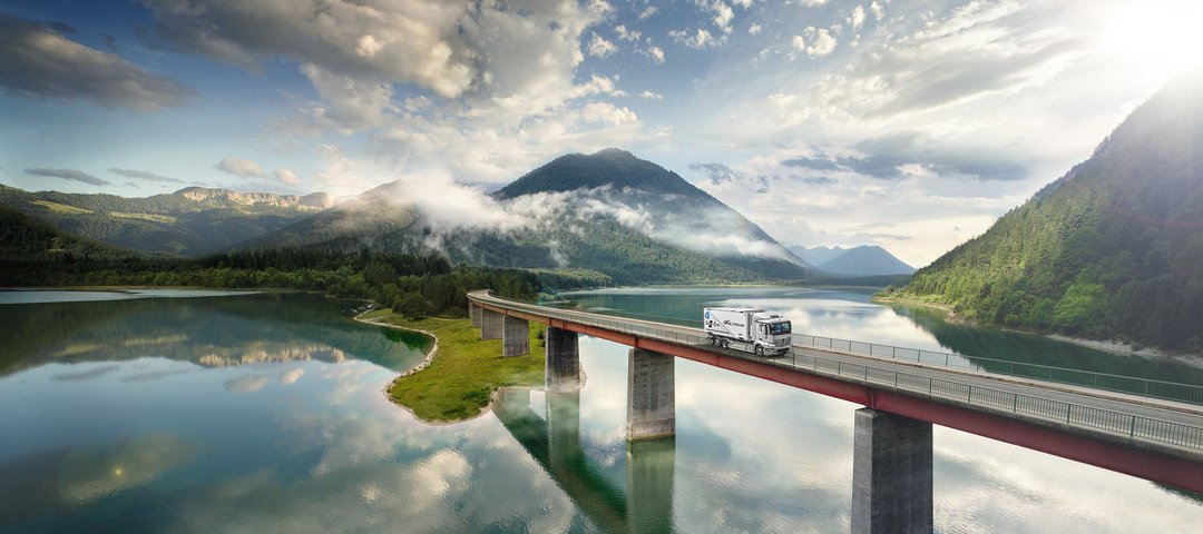 Mercedes-Benz eActros drives over a bridge over a lake in the mountains