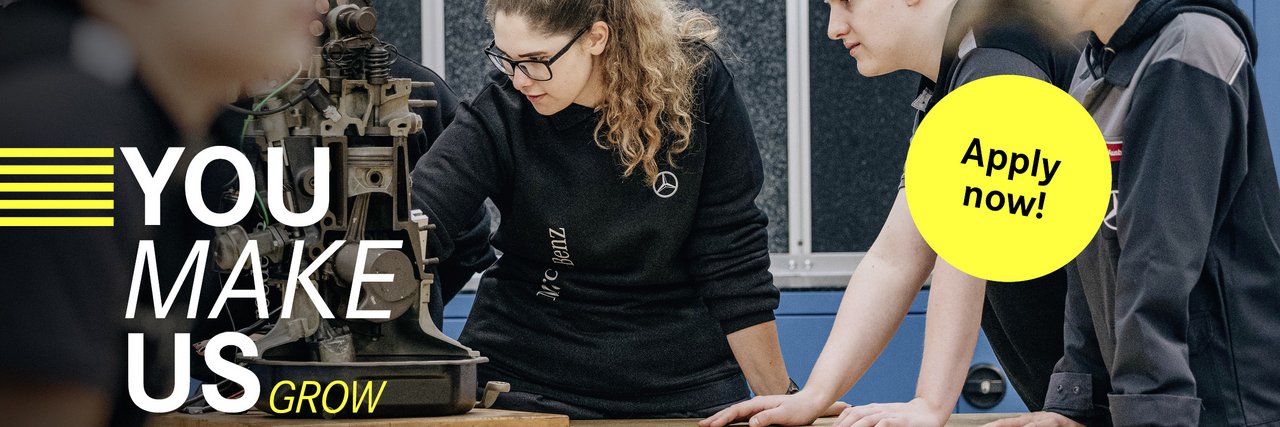 A group of young team members analyse a mechanical device in a workshop. The slogan "You make us grow" can be seen on the left-hand side, accompanied by a yellow button with "Apply now!"